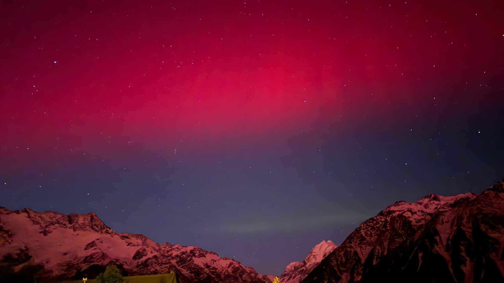 Red and pink Southern Lights above mountains in New Zealand