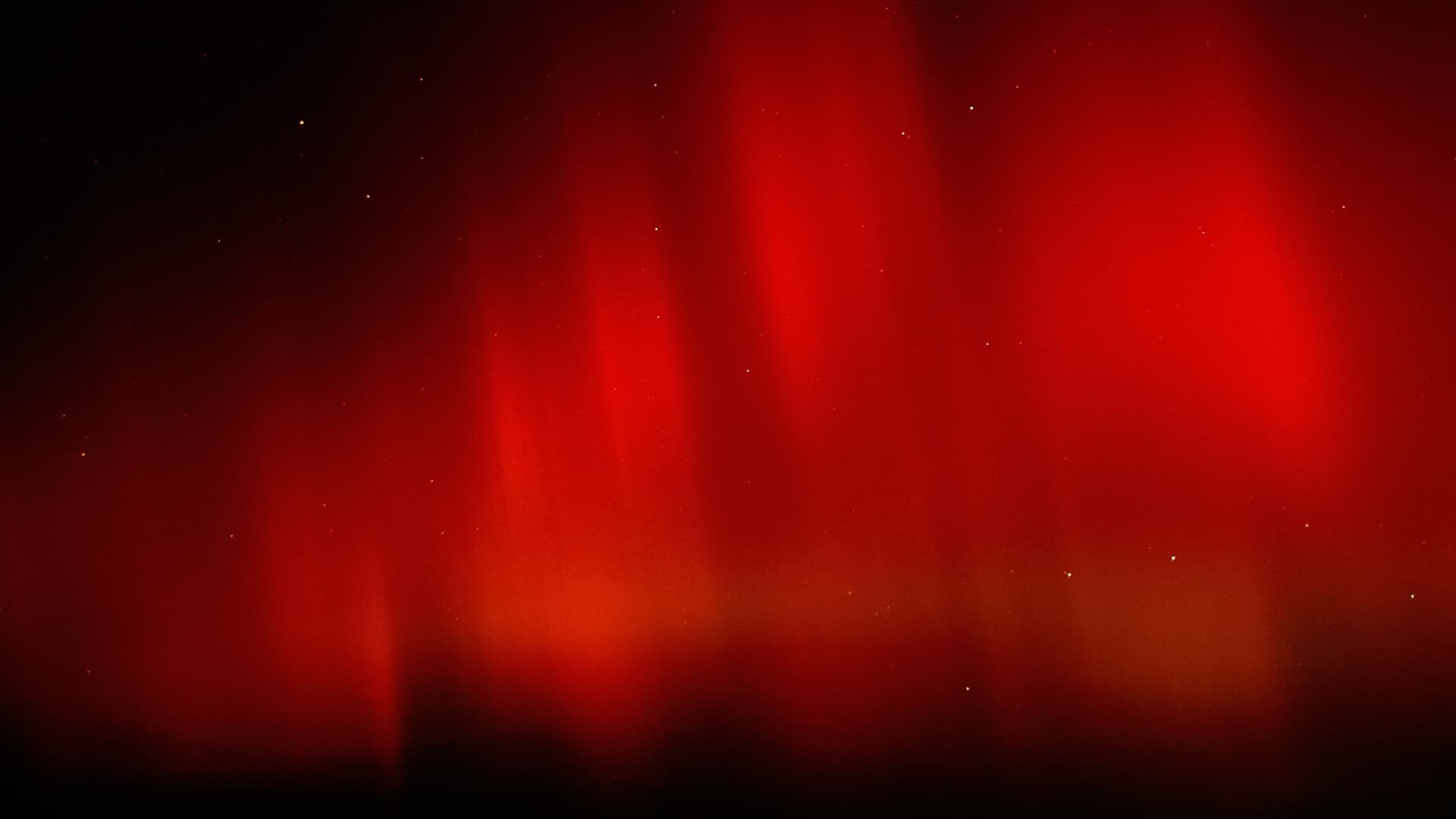 Intense red Northern Lights filling a dark, starry sky