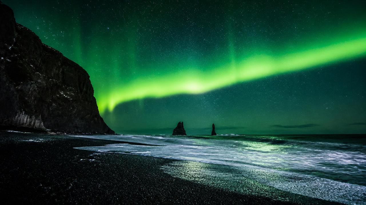 Northern lights over Reynisdrangar sea stacks at Vík's black sand beach